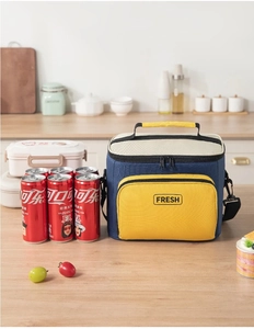 Navy and yellow insulated lunch bag with FRESH print next to soda cans on a table