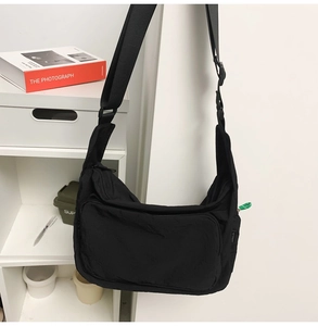 Close-up of black waterproof nylon messenger bag with adjustable strap and front pocket