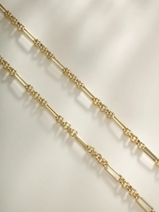 Macro shot of polished gold-plated rectangular link chain with intricate joint details