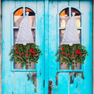 Christmas gnomes wreaths with red berries and pine needles hanging on a vintage blue door