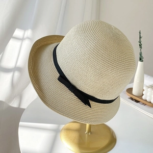 Elegant beige straw sun hat with black bow ribbon on a luxury display stand
