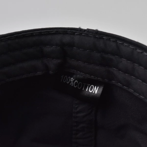 Detail showing the 100% cotton material tag and fine stitching on the black duckbill hat