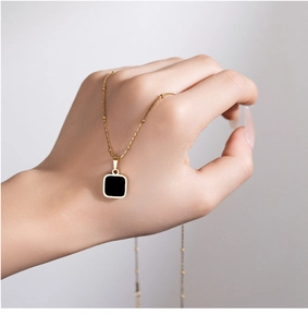 Detail view of 18k gold plated ball chain necklace with black square geometric pendant