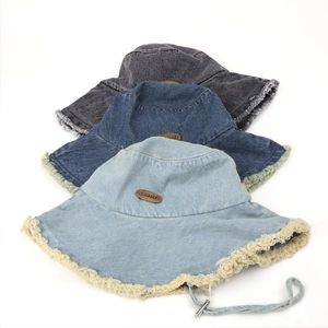 Detail of frayed edges and leather brand patch on denim bucket hats in three colors