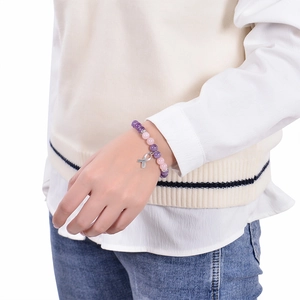 Gros plan d'un bracelet en perles roses et violettes avec pendentif ruban argenté