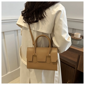 Detail of camel leather handbag showing a structured rectangular design and shoulder strap