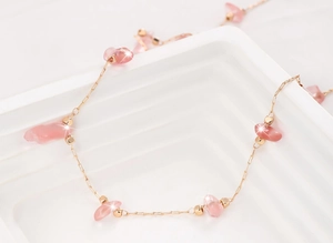 Macro detail of 14K gold-filled chain with strawberry crystal and pink quartz beads