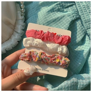 Three-piece set of floral and solid scrunchies displayed on a retail card