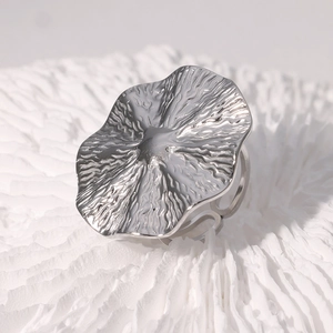 Close-up of silver geometric ring with unique wavy texture on white coral surface
