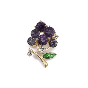 Detail of a vintage grape brooch with purple crystals and green enamel leaves