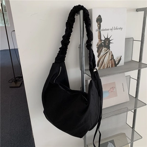 Dettaglio della borsa a mezzaluna in nylon nero con tracolla larga a pieghe