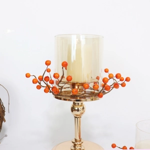 Goldener Kerzenhalter mit Glaszylinder und roten Beeren für festliche Tischdekorationen