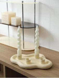 Détail du bougeoir en céramique crème avec bougies spirales sur une table en bois