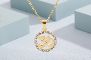 Macro view of gold circular Om pendant featuring sparkling rhinestones on the outer rim