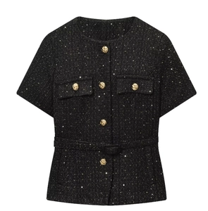 Dettaglio giacca in tweed nero con paillettes, bottoni dorati e cintura in vita