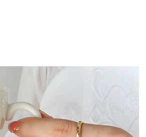 Gros plan sur une bague torsadée en acier titane doré avec des pierres précieuses