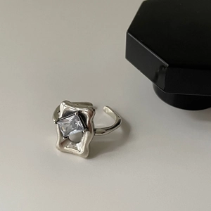 Close-up of a silver minimalist open ring featuring a sparkling square-cut clear gemstone