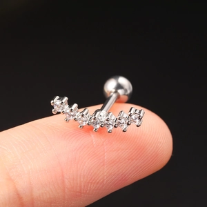 Macro shot of silver curved helix stud with seven sparkling zircons on a fingertip