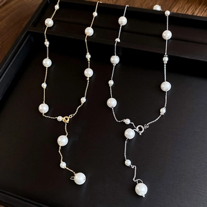 Detail view of gold and silver pearl tassel necklaces on a dark wood display tray