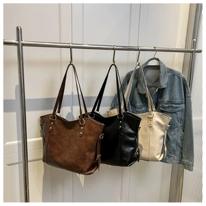 Detailed view of large tote bags in brown, black, and beige with metal rings and rivets