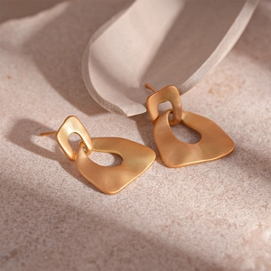 Macro view of matte gold irregular geometric earrings with textured metal finish