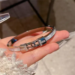 Detail of stainless steel T-motif bracelet with zircon stones and mother of pearl inlay