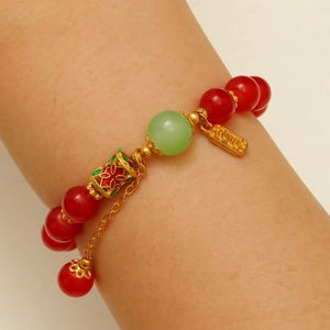Détail du bracelet en agate rouge et jade avec breloque dorée gravée 'Paix'