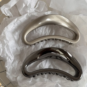 Close-up of crescent hair claws in matte champagne gold and sleek metallic gunmetal grey