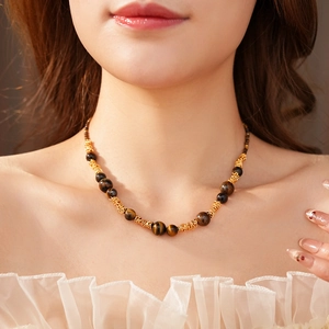 Gros plan du collier en œil de tigre avec chaîne dorée tissée sur le cou d'une femme