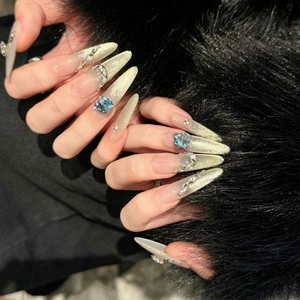 Unghie finte extra lunghe cat eye con cristalli blu e sfumatura champagne glitterata