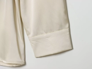 Vue détaillée de la manche de chemise en satin crème avec coutures de qualité et texture soie