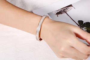 Détail d'un bracelet jonc en or rose avec pavé de diamants au poignet pour un look tendance