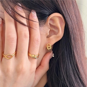 Detailed view of gold beaded earrings and knot ring set on a fashion model
