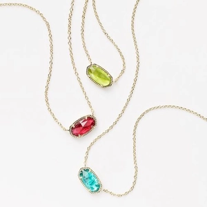 Detailed view of three gold necklaces with green, red, and blue faceted stone pendants
