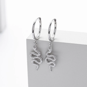 Macro detail of silver S925 sterling silver snake earrings hanging on a white cube