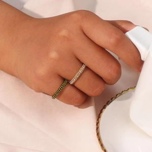 Minimalist gold and green zircon stackable rings worn by a model in a luxury setting