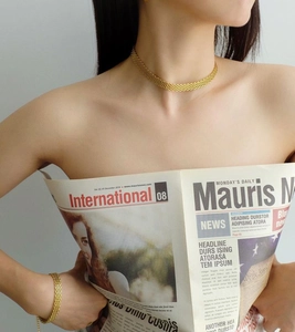 Dettaglio della collana e del bracciale a maglia dorata indossati da una modella