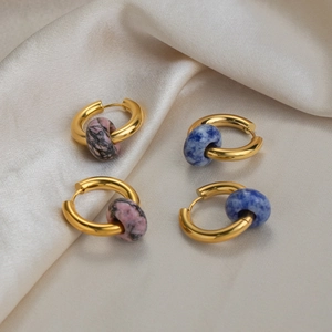 Golden hoop earrings with lapis lazuli and pink stone beads on beige silk fabric