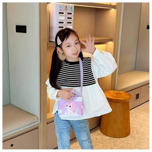Toddler purple unicorn crossbody bag shown by a smiling girl in a modern room setting