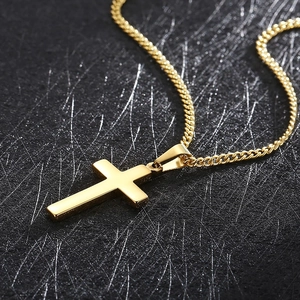 Vue détaillée d'un pendentif croix en acier inoxydable doré avec une chaîne à mailles gourmette