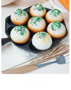 Detailed view of artificial pan-fried buns in a black cast iron pan with garnishes