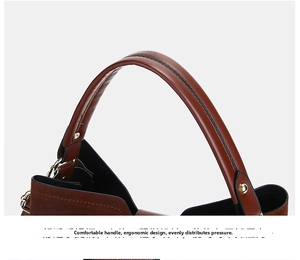 Ergonomic leather handle with gold metal hardware on a brown suede shoulder bag