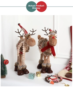 Detail of plush Christmas reindeer dolls with festive hats and knit scarves on table