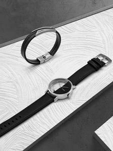 Close-up of minimalist black leather watch and matching leather bracelet set for men and women