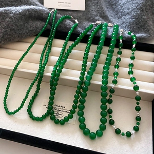 Vue détaillée de colliers de perles en verre vert émeraude sur un plateau à bijoux