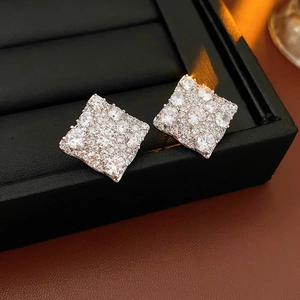 Gros plan de boucles d'oreilles carrées en zircone pavée sur un support de bijoux noir