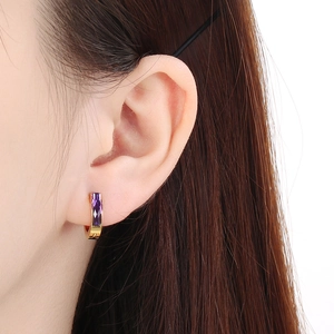 Macro shot of gold-plated huggie earring with rectangular purple zircon stone