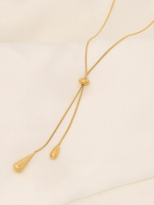 Close-up of golden teardrop pendant necklace with adjustable slide on silk fabric