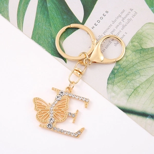 Detailed view of golden letter E keychain with crystal rhinestones and butterfly charm