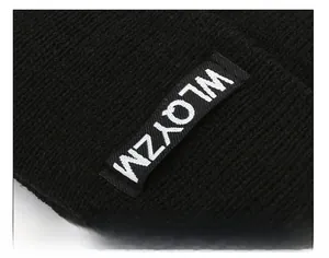 Close-up of black knitted beanie showing detailed texture and a minimalist logo tag